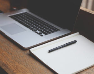 Computer and blank notebook on a desk