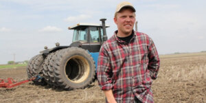 Farmer standing in front of a tractor in a field