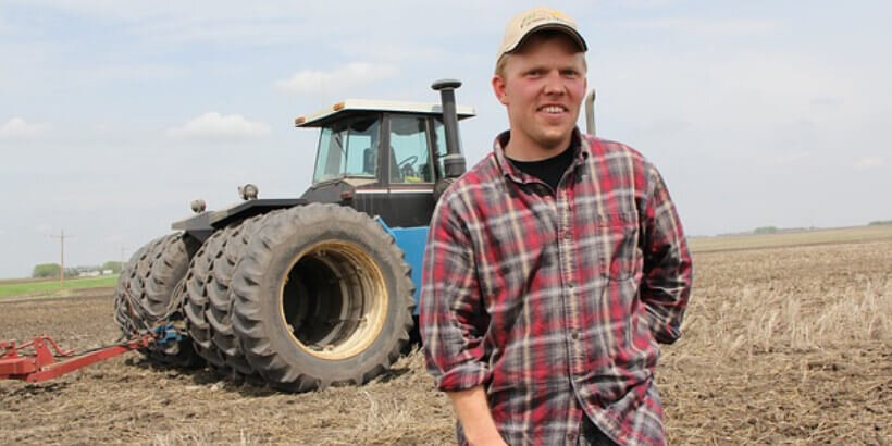 Farmer standing in front of a tractor in a field