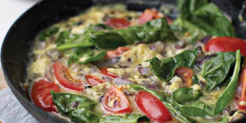 A cast iron skillet with a tomato and spinach frittata