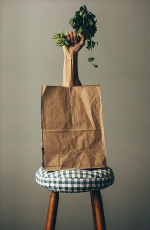 hand holding leafy green coming out of bag on stool