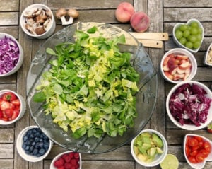 fruit and vegetables surrounding lettuce in a bowl