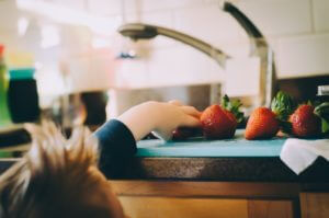 kid reaching for strawberries