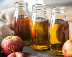 apples next to apple cider in bottles